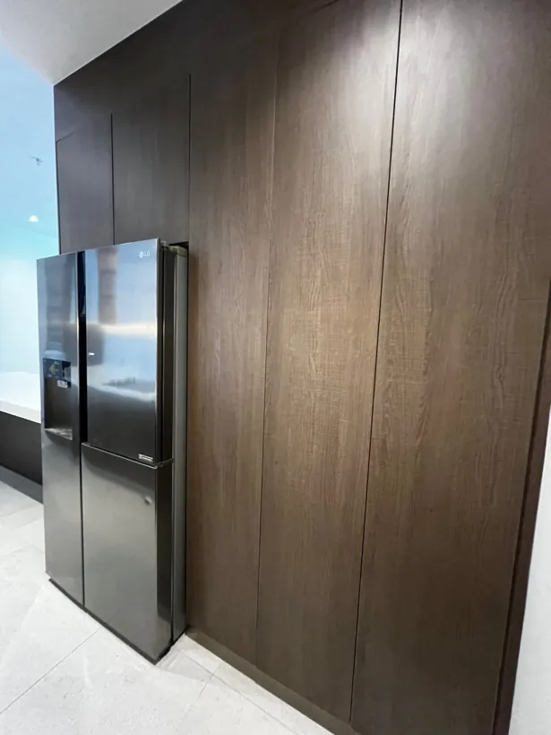 Muro de alacenas de piso a techo junto al refrigerador, con puertas sin jaladera
